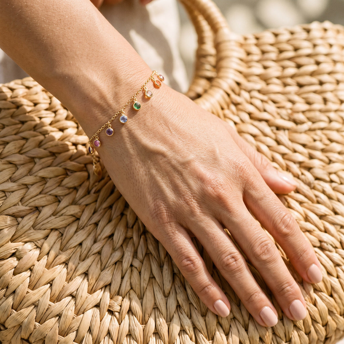 Woman wearing the Ocean Aura Charm Bracelet with her hand on a rattan beach bag