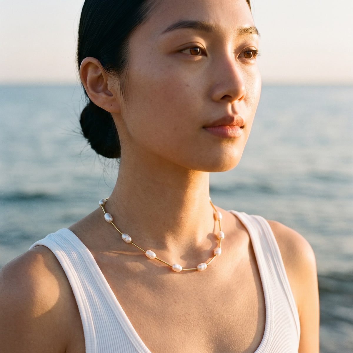 Woman wearing the Maldives pearl necklace by the sea