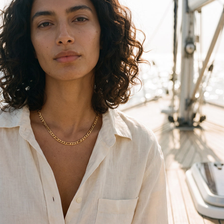 Woman wearing the gold Positano figaro necklace on a sailboat